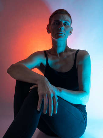 Portrait of a woman. Red hair. She is brooding. In a studio. Close-up.