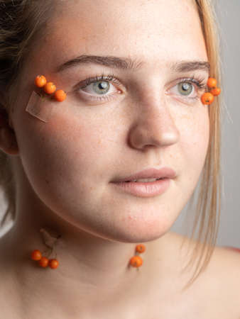 Portrait of a young girl with freckles decorated with rowan on her face.の写真素材