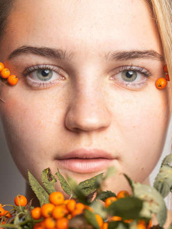 Portrait of a young girl with freckles decorated with rowan on her face.の写真素材
