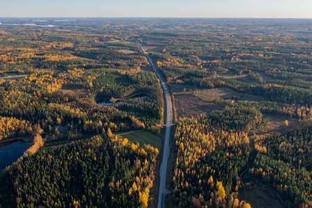 Finland, autumn landscape from the air with a drone, driving road, lakes and pine forest, on a sunny...