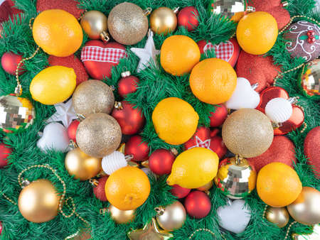 Christmas background with a green tree, red and gold balls, oranges and lemons. Merry Christmas and...