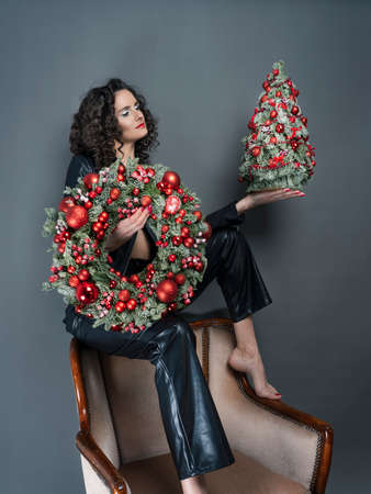 Brunette woman in hands with decorations for Christmas. Christmas tree and wreath. There is a place for text. Concept of gifts for Christmas, for the New Year.の写真素材