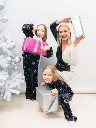 Two girls and mom at the Christmas tree with gifts. Holiday concept, vacations, vacations.の写真素材