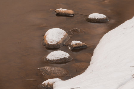 Stones in the stream. a small river in a snowy forest close-up.. Winter nature.の写真素材