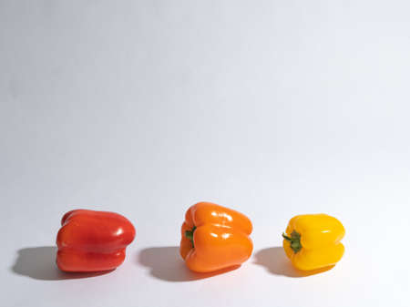 Three peppers, yellow, red, orange on a white background. There is space for textの写真素材