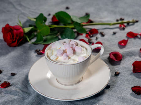 Coffee in a white cup and marshmallows. with a rose on a brown background. The concept of congratulations, Valentine's Day, mother's dayの写真素材
