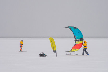 Finland. Espoo. January 29, 2022 . On the ice in the sea a group of kite surfers, they are skiing, bad weather, strong wind and blizzardのeditorial素材
