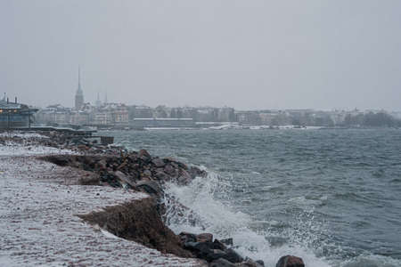 View of Helsinki from the seashore in a winter storm, waves breaking on a rocky shore. Finland weather.の写真素材