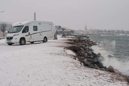 Finland. Helsinki. January 29, 2022 view of the city and the sea in a winter storm, the waves break on the rocky shore. People in cars are watching the storm. Finland weather.のeditorial素材