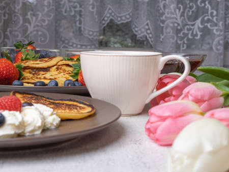 Sweet homemade pancakes with blueberries and strawberries jam and sour cream. tea on a white...