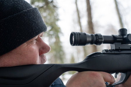 A man with a rifle in the spring forest, the hunter holds a rifle and waits for prey, the hunter shootsの写真素材