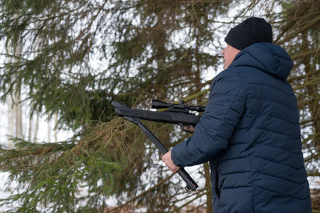 A man with a rifle in the spring forest, the hunter holds a rifle and waits for prey, the hunter shootsの写真素材