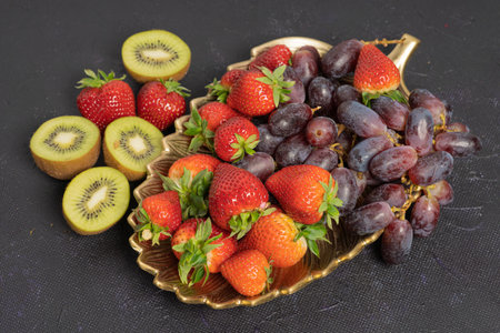 Strawberries and grapes, kiwi in a beautiful vase. top view. on a black background. Thesis concept, vitaminsの写真素材