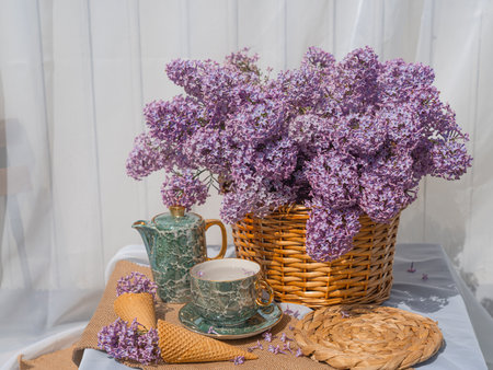 A bouquet of lilacs in a basket and a tea set. Ice cream waffle cones are decorated with flowers. side view background whiteの写真素材