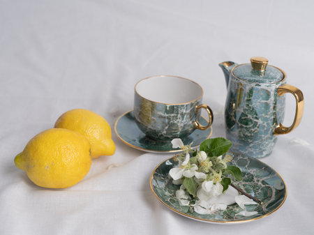 Still life in vintage style with a tea set, juicy lemons and apple blossoms on a white background. Time for tea. Space for text.の写真素材