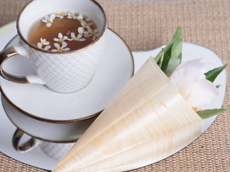Artistic still life. A cup of tea with small white flowers. Pink peony flower in a horn. Flowers for design.の写真素材