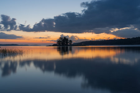 The reflection of the sky in the water at sunset. Orange sunset and dark clouds. Bright dramatic sky. Nature of Finland. Scandinavia. natural background.の写真素材