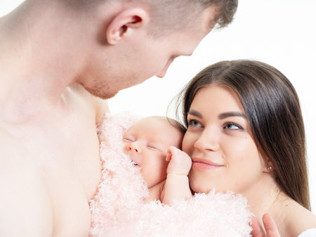 Parents hold a newborn baby in their arms. On a white background, in the studio. close upの写真素材