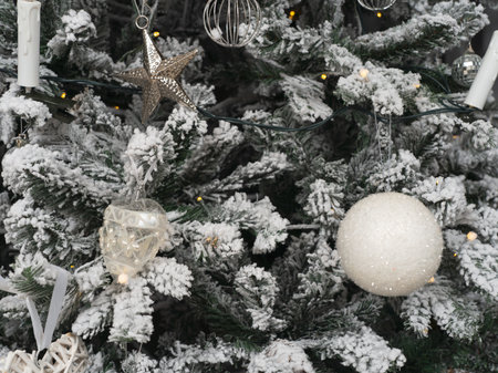The Christmas tree is covered with frost and decorated with balls, garlands, stars. Silver colors. close-up.の写真素材