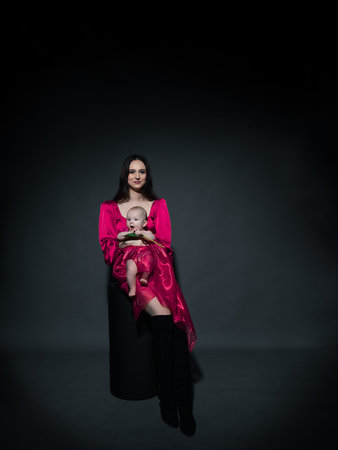 A young, modern, beautiful loving mommy holds hands, kisses her adorable baby in a bodysuit, expresses affection, feels love, close-up. Happy mother's day, motherhood, carefree childhood, guardianship conceptの写真素材