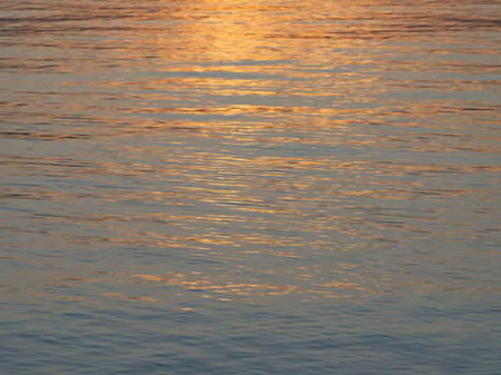Very beautiful reflection in the water of the rays of the sunset. Ripples on the water. Close-upの写真素材