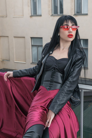 Woman with long hair, perfect figure, sexy. she is in a satin, long red skirt, leather jackets. Posing in the cityの写真素材
