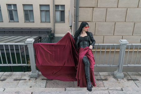 Woman with long hair, perfect figure, sexy. she is in a satin, long red skirt, leather jackets. Posing in the cityの写真素材