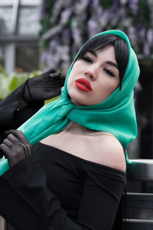 A brunette woman and red lips in a black dress, a bright scarf on her head. close-up portraitの写真素材