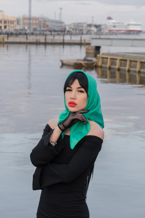 A brunette woman and red lips in a black dress, a bright scarf on her head. close-up portraitの写真素材