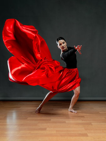 Dancer in a bright red skirt. Female dancer in a black bodysuit on a gray background.の写真素材