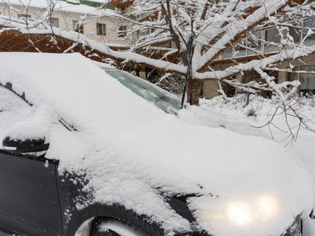 A cropped image of a black car covered in a thick layer of snow. The door handles and windows are partially visible beneath the snow, emphasizing the frosty and wintry atmosphere.の写真素材