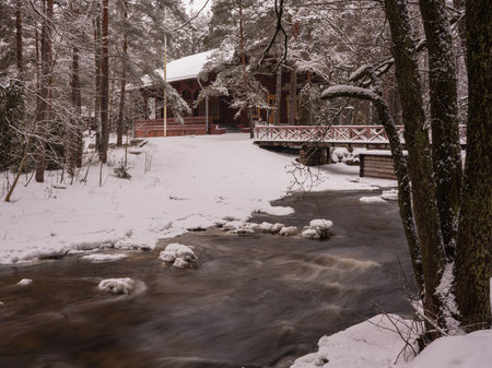 Winter landscape with a river and a wooden house in the forest.の写真素材
