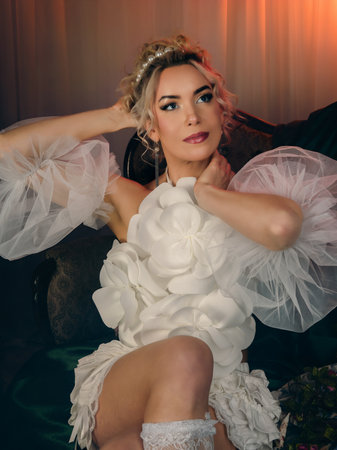 Beautiful bride in a wedding dress sitting on a chair in the roomの写真素材