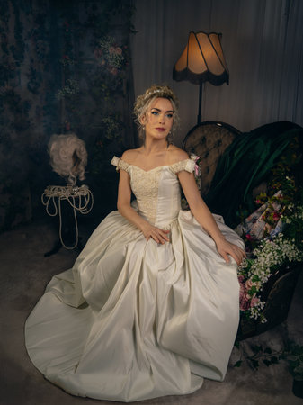 Beautiful young woman in a white wedding dress posing in the interiorの写真素材