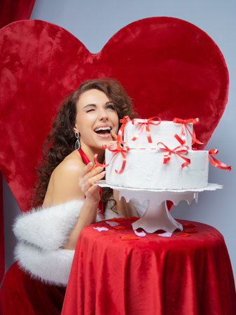 holidays and people concept - smiling young woman in santa helper costume with big cake over gray backgroundの写真素材