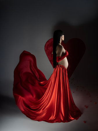 Brunette woman in red cloth with red heart on dark backgroundの写真素材