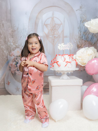 Cute little girl in pajamas with a cake and balloonsの写真素材