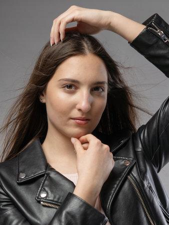 Portrait of a beautiful young brunette woman in a leather jacketの写真素材