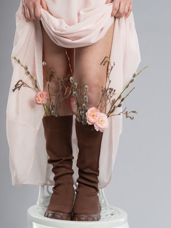 Beautiful female legs with flowers on a white background in the studioの写真素材
