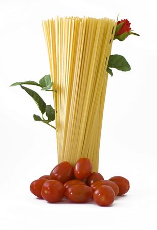 raw spaghetti standing with tomatoes on the base and a flowered red rose upの写真素材
