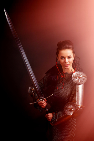 portrait of a medieval female knight in armor on a gray background with a side red light