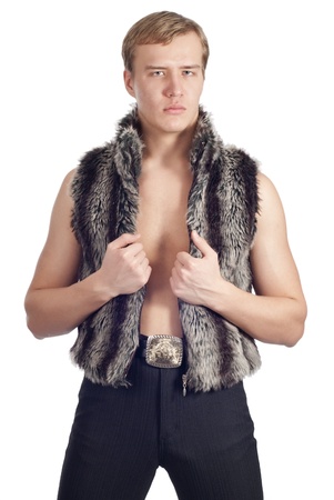 Young handsome man posing in studio in fur waistcoat over whiteの写真素材