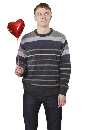 Young handsome man with red heart balloon over whiteの写真素材