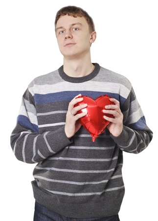 Young handsome man with red heart balloon over whiteの写真素材