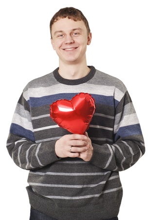 Young handsome man smiling with red heart balloon over whiteの写真素材