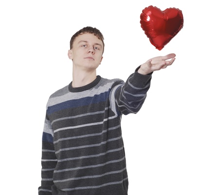 Young handsome man with red heart balloon over whiteの写真素材