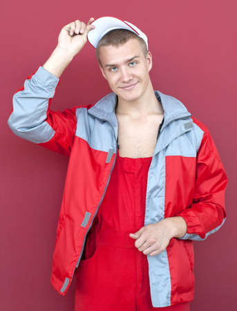 Young handsome smiling worker over red backgroundの写真素材