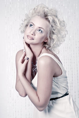 Attractive blond beauty in white dress with original make up and hair dress posing in studioの写真素材