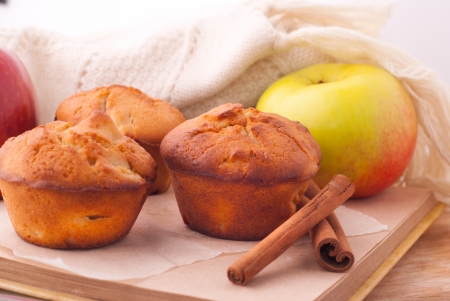Muffins with red apple and cinnamon sticks on open bookの写真素材