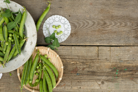 green peas on rustic wooden background in old metal plate 